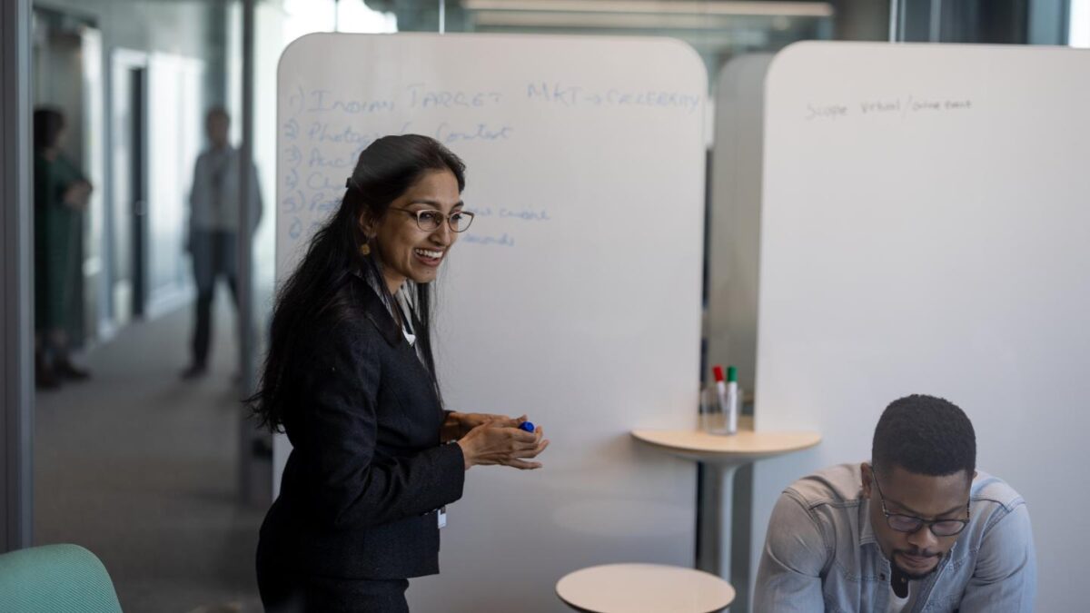 Preethi Rahomman in front of a whiteboard talking to other MBA students
