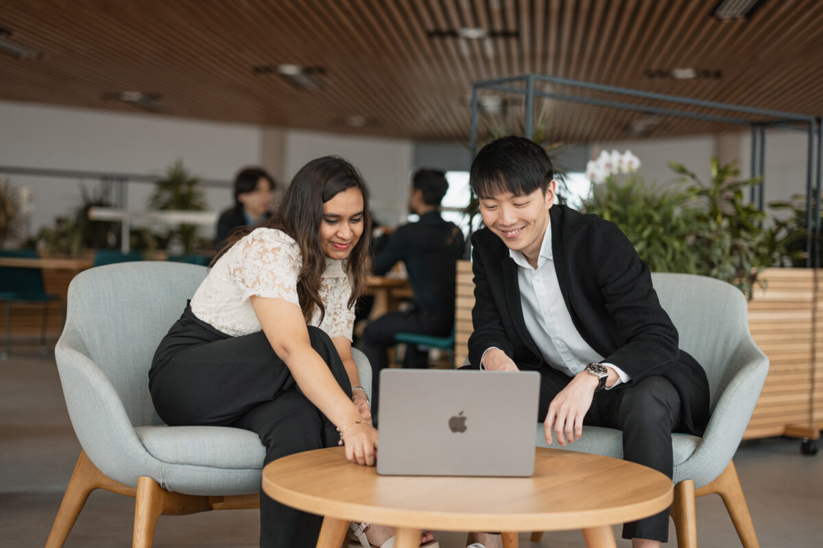 Two MBA students looking at a laptop and smiling