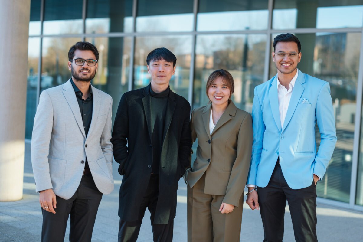 Four MBA students standing outside the School of Management building